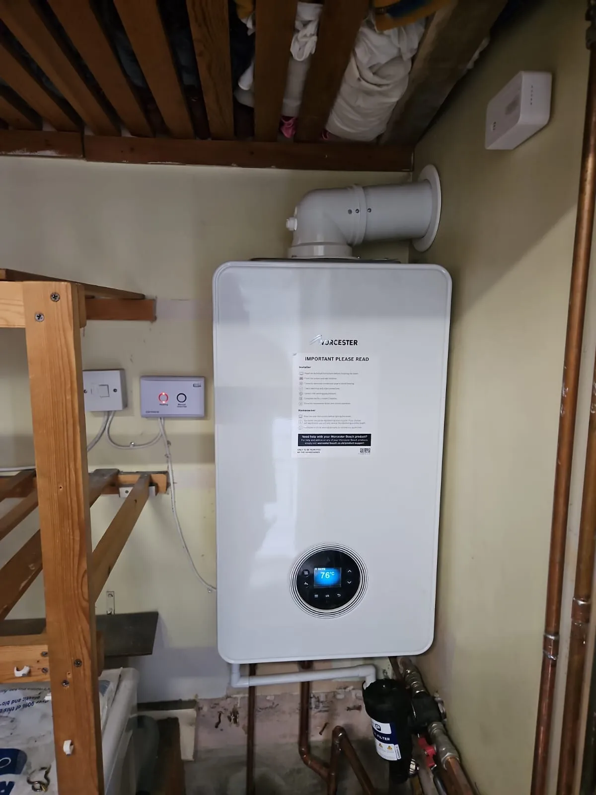A professional boiler installation in Slough, showing a new Worcester boiler with its manual attached, a digital display showing the temperature, and a magnetic filter installed on the connected pipework.