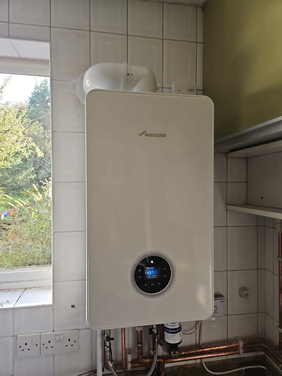 An image showing a professional boiler installation in Slough, featuring a modern Worcester Bosch boiler mounted on a tiled wall with visible copper piping and a smart digital display.
