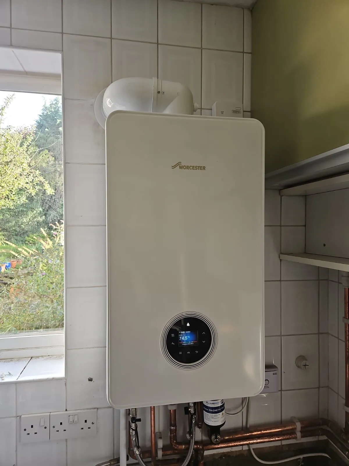 An image showing a professional boiler installation in Slough, featuring a modern Worcester Bosch boiler mounted on a tiled wall with visible copper piping and a smart digital display.