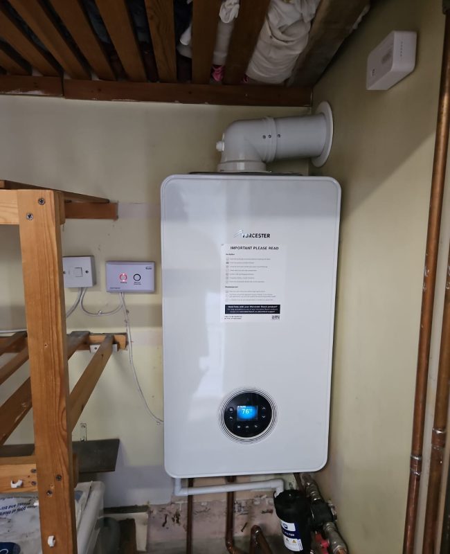 A professional boiler installation in Slough, showing a new Worcester boiler with its manual attached, a digital display showing the temperature, and a magnetic filter installed on the connected pipework. A professional boiler installation in Slough, showing a new Worcester boiler with its manual attached, a digital display showing the temperature, and a magnetic filter installed on the connected pipework.
